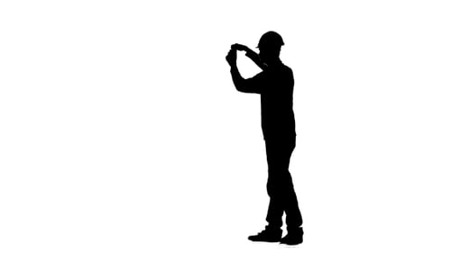 Engineer in a Helmet Measures Roulette Measurements for the Drawing. Silhouette. White Background