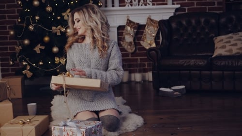 Woman Enjoys Christmas with Presents by Fireplace