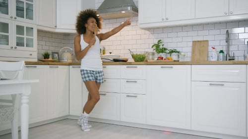 Woman Singing and Dancing in Bright Kitchen