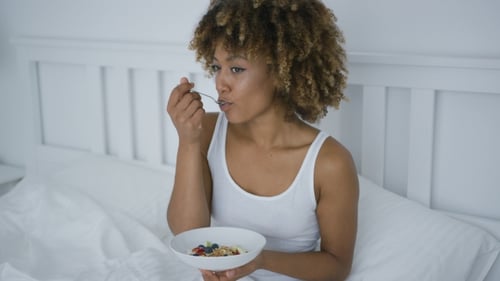 Young Woman Eating Breakfast in Bed