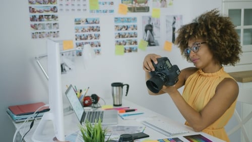 Woman Inspecting Camera in Bright Office