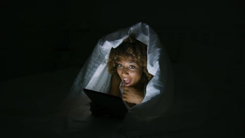 Excited Woman Under Blanket with Tablet