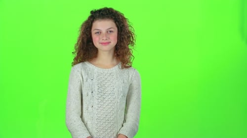 Baby Smiles and Looks Into the Distance, Covering Her Face with Her Hands. Green Screen