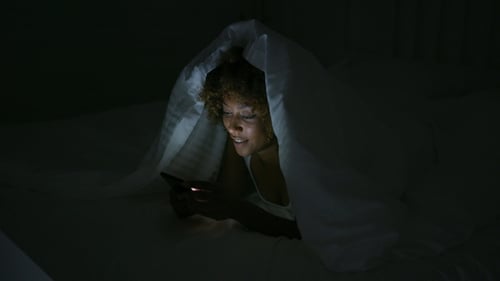 Young Woman Using Phone in Dark Room