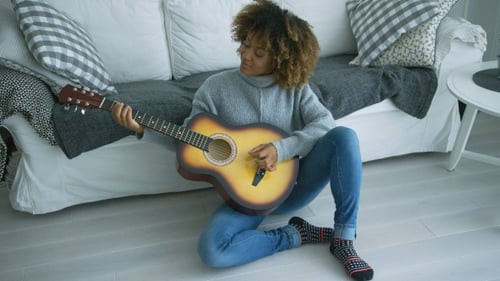 Young Woman Plays Guitar at Home