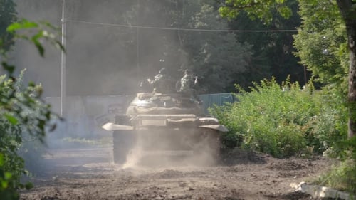 Military Soldiers Sitting on War Tank Moving on Road at Shooting Range