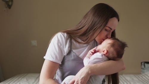Loving Mother Holds Sleeping Infant in Bedroom