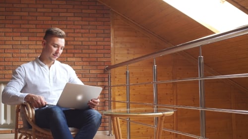 Young businessman working with documents and laptop sitting by desk in office.