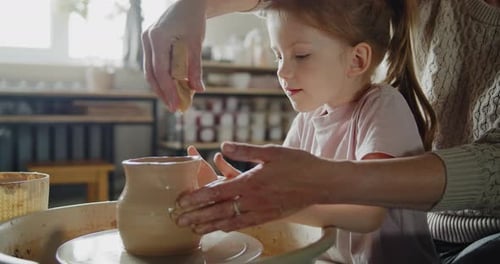 Child Learning Pottery with Adult Instructor