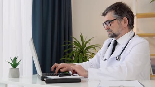 Senior Doctor 50s Works in Laptop