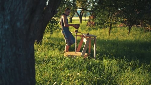 Équipement spécial de potier sous un grand arbre vert, un jeune potier professionnel apporte de l'eau