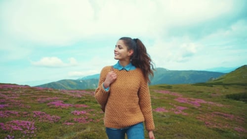 Young Woman Hiking Through Mountain Meadow With Wildflowers