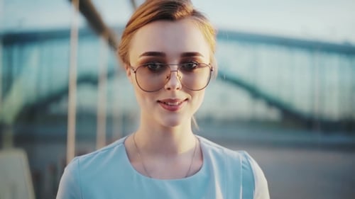 Elegant Woman with Sunglasses Smiling in Urban Setting