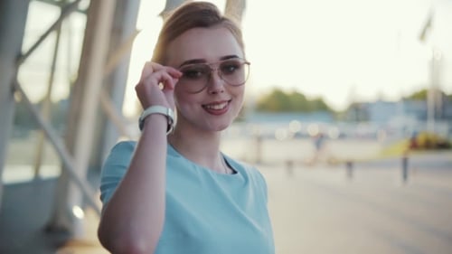 Attractive Young Lady Walking Down the Airport Terminal in a Bright Sunlight, Then Turns To Camera