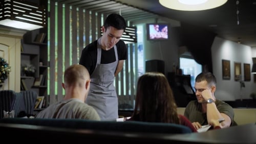 Waiter Serving Guests in Cafe