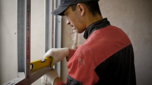 A Young Worker Who Works at a Construction Site Works with Aluminum Profiles, Tools for Measuring