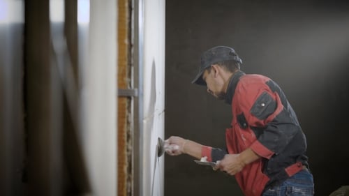 Man Applying Plaster To Wall With Trowels