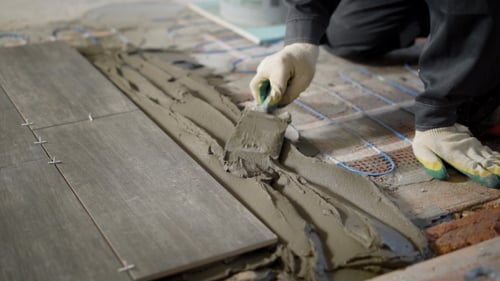Shot of the Builder Hands in Gloves, Who Puts the Cement Mixture on the Brick Floor