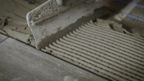 the Process of Leveling the Cement with a Spatula, the Foreman Holds a Tool in His Hand and Guides