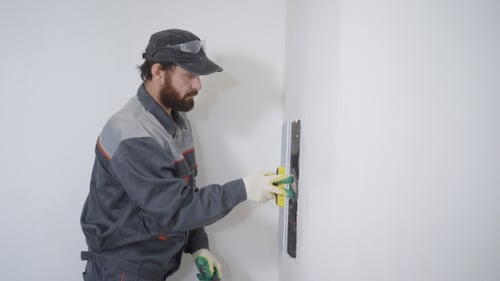 Man Applying Plaster to Wall Indoors