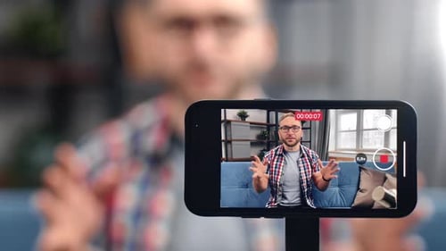 Freundlicher männlicher Blogger, der Video aufnimmt Verwenden Sie den Smartphone-Bildschirm, der mit dem Publikum