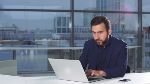 Portrait of Businessman in Office with Laptop Computer.
