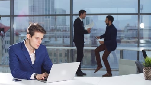 Portrait of Businessman in Office with Laptop Computer.