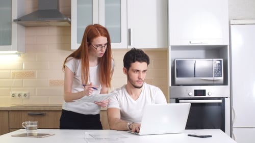 Woman and Man Working Together on Laptop in Kitchen