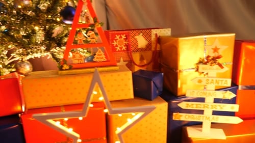 Weihnachtsgeschenke am Fuße des Baumes mit brennenden Kerzen.