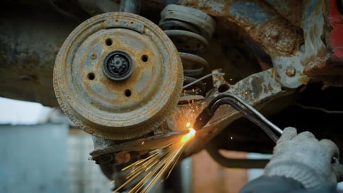 Shot of a Worker Uses a Cutting Torch To Cut a Large Metal Object Into Pieces at a Metal Recycling