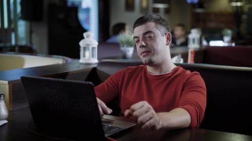 Handsome Man travaille sur un ordinateur portable au café.