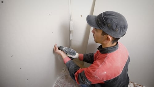 Young Adult Screws Drywall to Wall