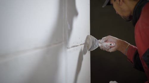 Man Sealing Drywall Seams with Spackle