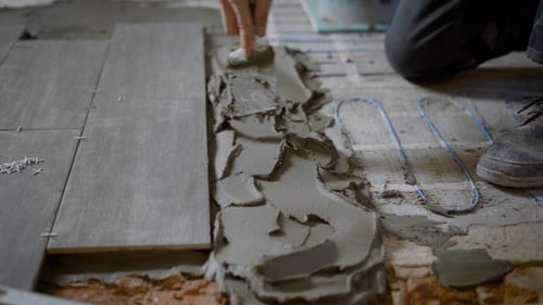 Homme anonyme appliquant du ciment sur le sol pendant qu'il travaillait sur le site