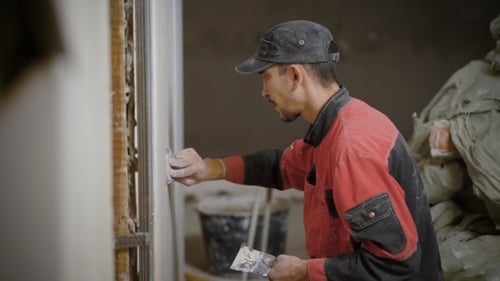 Man Applies Plaster to Wall Indoors