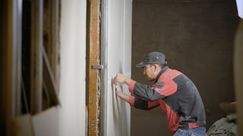 Man Spackling Drywall Indoors