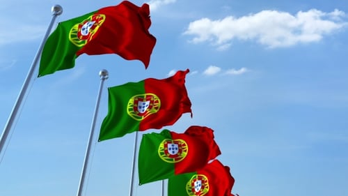 Multiple Portugal Flags Waving in Blue Sky