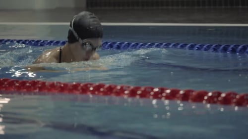Young Woman in Goggles Swimming Breaststroke in Blue Water Swimming Pool