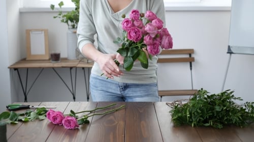 Woman Arranging Pink Roses in a Bouquet