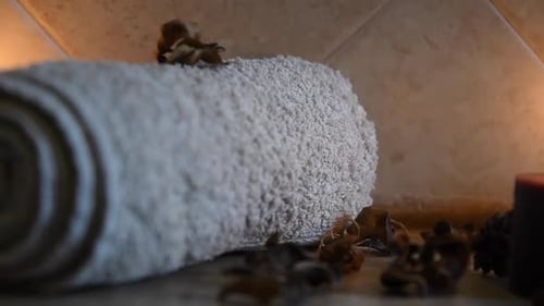 Entspannender Spa-Hintergrund mit Kerzen mit flackernden Flammen, einigen Holzblättern und einem Handtuch