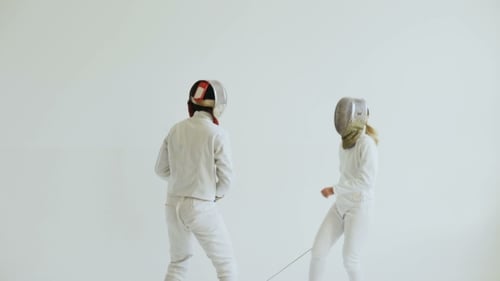 Young Woman Fencer Having Fencing Training with Trainer in White Studio Indoors