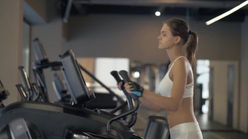 Woman Exercising on Elliptical Machine at Gym