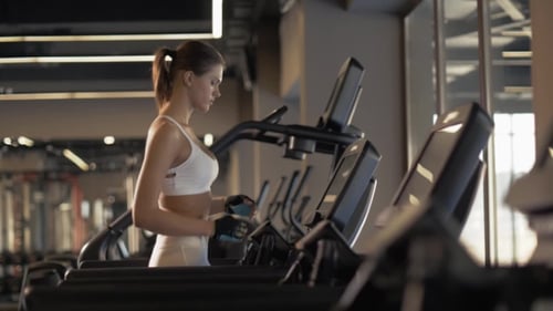 Sports Woman Using Screen on Treadmill for Settings Cardio Exercise in Gym Club