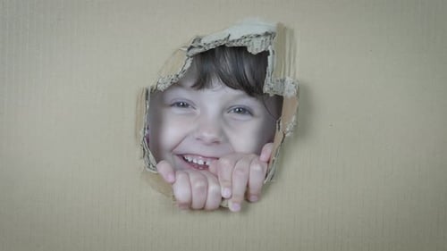 Happy Child Smiling Through a Hole in Box