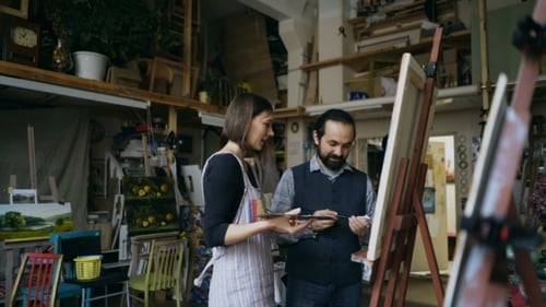 Un artiste souriant apprend à une jeune fille à dessiner des peintures et explique les bases dans un studio d'art