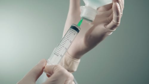 der Arzt nimmt das Medikament in einer Spritze auf und bereitet sich auf eine Injektion vor