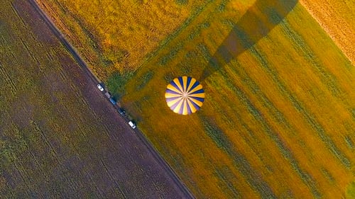 Envelope of Hot Air Balloon Landed Floating in Air, Casting Shadow Over Field