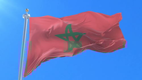 Waving Moroccan Flag on Pole Against Blue Sky