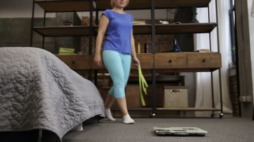 Woman Steps onto Scale with Measuring Tape