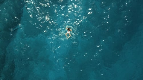 Girl in a White Swimsuit Swimming in the Blue Sea